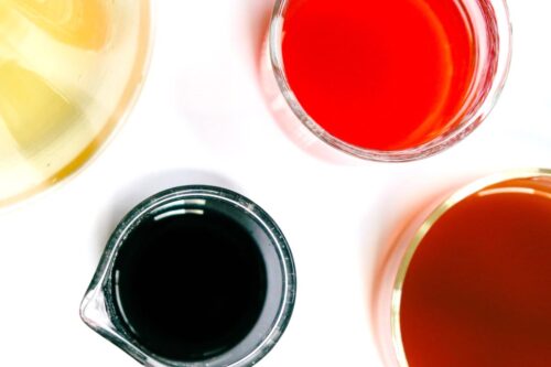 Glass cups with differently coloured liquids viewed from above.