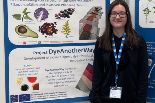 Natalia Kastana standing in front of her poster presenting it at the Lange Nacht der Forschung 2026